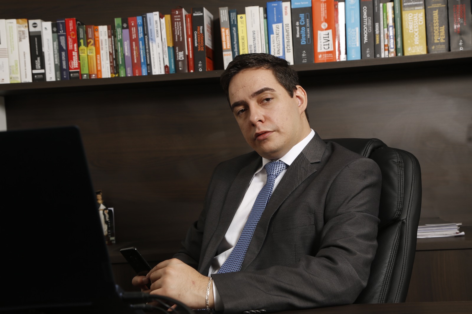 Eduardo Castilho em seu escritório em Cafelândia, sentado à mesa diante de uma estante de livros.